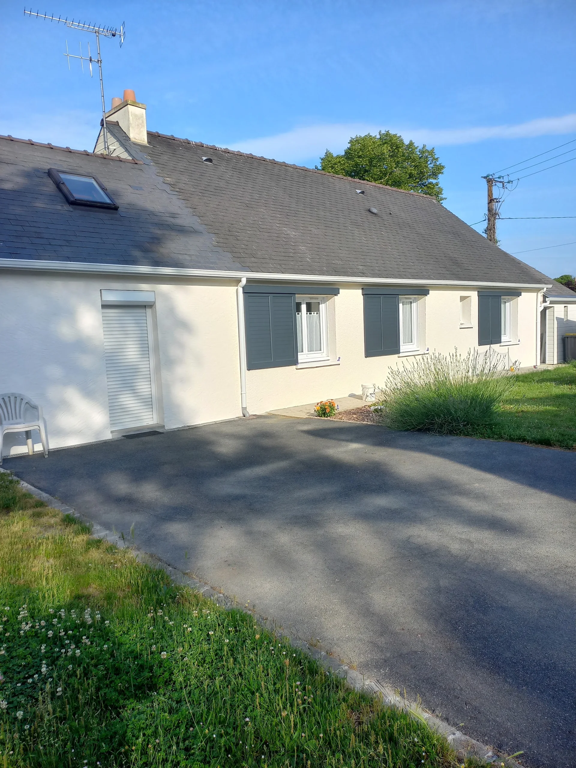 Façade claire d’une maison avec volets blancs et toiture en ardoise