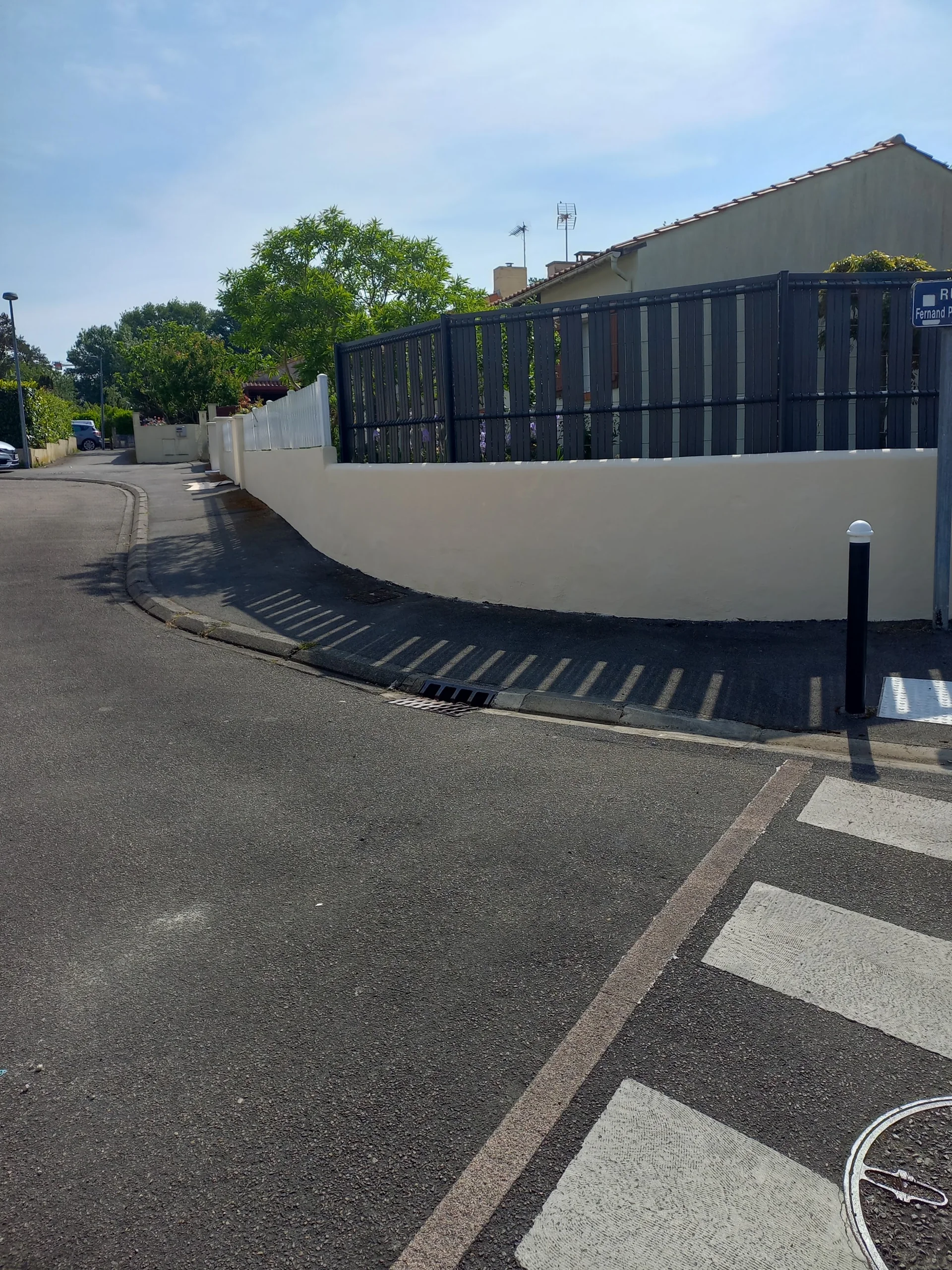 Mur clair avec une clôture sombre en bord de rue